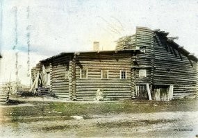 Особенно доставляет крестьянин на заднем плане - в шляпе, костюме-тройке и при галстуке. 
Судя по найденной информации, фотография из коллекции некоего А.В.Живаго (доктор, член Русского фотографического общества), 1897 год . 
Семья, запечатлённая на фото, явно не простая крестьянская. Справный дом под железной крышей, водостоки, кирпичный фундамент, большие застеклённые окна с кружевными занавесями, резьба и витые столбики, мальчик в сапожках по размеру... 
Видимо, сельские богатеи, кулаки. 
Сравните с настоящей крестьянской семьёй и с типичным деревенской избой, объединяющей под одной крышей жилую зону и хлев с конюшней.