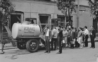 Ну, по сравнению с остальными картинками эта, более достоверна. Не было в СССР ТАКИХ трехколесных великов. Основной детской лошадкой был "Ветерок" (со съемным, кстати, третьим колесом, переделывался в двухколесный). Клумба слишком "навороченная", были, но намного более примитивные. Есть и более серьезная ошибка. Никогда не задумывались, как в этих бочках мыли посуду-кружки? А ведь "хоть как то" мыли же. Одноразовой в СССР почти не было, да и на рисунке кружка стеклянная (так и было). Вот справа от крана был фонтанчик с рычажком на дне ниши. Ставили на него кружку дном вверх открывали кран и несколько секунд смывали внутри кружки. Поэтому абсолютно ВСЕ эти бочки, хоть с квасом, хоть с пивом ставили, в сезон, в специально оборудованных местах. Из подвальчика ближайшего дома, из люка в парке вылезала трубка, к ней шланг и этот шланг прикручивался снизу к нише бочки и "запитывал" фонтанчик. Под отработанную воду были варианты. Либо ставилось ведро, которое продавец периодически опорожнял на газон или в ливневку или еще один шланг который тоже уходил на газон или в ливневку или просто из него тек ручеек вдоль дороги. Понятно, что выглядело это не слишком эстетично. На картинке решили сделать красивее. Вот реальная "схема" монтажа :)