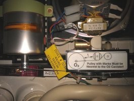 Boeing-737 NG
В верхней и нижней (по фото) частях PSU находятся отсеки кислородных масок пассажиров.
Кислород в маски поступает по серому шлангу, виден с правой стороны.

Кислород к ним поступает из химических генераторов. Металлический цилиндр на фото. Это и есть Oxygen generator. По одному такому генератору приходится на каждый двойной или тройной блок кресел.

Генератор вырабатывает кислород в результате химической реакции хлората натрия с железом, и остановить его невозможно.
Длительность его работы порядка 15 минут. Во время работы генератор нагревается до температуры порядка 230 градусов. Оранжевая полоска на корпусе генератора чернеет при нагреве и показывает, что генератор использован.

В левой части генератора видно устройство его запуска.

Принцип тут примерно как у ручной гранаты - есть подпружиненый боёк, который удерживается небольшим штырём.
Как только штырь вытащен, боёк ударяет в запал и таким образом инициирует химическую реакцию.
Штырь вытаскивается только чисто механически, никакого электропривода нету.
Тросик от штыря через систему колёсиков соединяется с верёвочками, на которых повисают вывалившиеся кислородные маски: