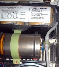 Boeing-737 NG
В верхней и нижней (по фото) частях PSU находятся отсеки кислородных масок пассажиров.
Кислород в маски поступает по серому шлангу, виден с правой стороны.

Кислород к ним поступает из химических генераторов. Металлический цилиндр на фото. Это и есть Oxygen generator. По одному такому генератору приходится на каждый двойной или тройной блок кресел.

Генератор вырабатывает кислород в результате химической реакции хлората натрия с железом, и остановить его невозможно.
Длительность его работы порядка 15 минут. Во время работы генератор нагревается до температуры порядка 230 градусов. Оранжевая полоска на корпусе генератора чернеет при нагреве и показывает, что генератор использован.

В левой части генератора видно устройство его запуска.

Принцип тут примерно как у ручной гранаты - есть подпружиненый боёк, который удерживается небольшим штырём.
Как только штырь вытащен, боёк ударяет в запал и таким образом инициирует химическую реакцию.
Штырь вытаскивается только чисто механически, никакого электропривода нету.
Тросик от штыря через систему колёсиков соединяется с верёвочками, на которых повисают вывалившиеся кислородные маски: