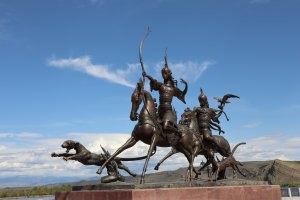 Как раз недавно был в Кызыле, и на экскурсии по городу нам, конечно, рассказывали про Даши. 
Экскурсовод обратила особое внимание, что это во-первых это не охотничьи собаки, а кошки - видимо, гепарды, или еще кто-то. А во-вторых - впереди едет женщина и ее головной убор намного выше, чем у мужчины, что указывает на ее более высокое положение в обществе. Просто, любопытные факты))