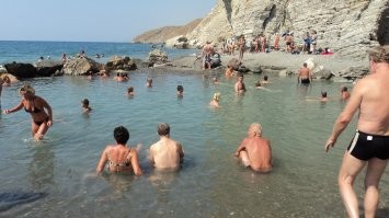 В Греции, на острове Кос, есть сероводородный источник почти горячей воды, бьющей из скал и стекающий прямо в Эгейское море. Люди с помощью камней отгородили часть моря , создали, некоторым образом, "замкнутый" бассейн. И туристы с большим удовольствием принимают эти тёплые сероводородные ванны.
Запах вокруг "озерца" весьма чувствителен.
Серебряные украшения после купания в нём приобретают бронзовый оттенок.