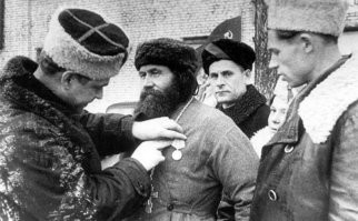 Отвечу пожалуй...
Командир 5-й Ленинградской партизанской бригады, Герой Советского Союза К.Д. Карицкий прикрепляет медаль «Партизану Отечественной войны II степени» священнику церкви псковского села Хохловы Горки Порховского района Федору Пузанову (1888-1965).
В годы войны Федор Андреевич Пузанов стал разведчиком 5-й партизанской бригады. Георгиевский кавалер Первой мировой войны и скромный сельский плотник в 30-е годы, он, пользуясь относительной свободой передвижения, разрешенной ему оккупантами как священнику сельского прихода, вел разведывательную работу, снабжал партизан хлебом и одеждой, сообщал данные о передвижениях немцев. Кроме этого, он вел беседы с верующими и, передвигаясь от села к селу, знакомил жителей с положением в стране и на фронтах.
Во время эвакуации немцами населения Псковского района в январе 1944 г. священник Пузанов должен был сопровождать свой приход к месту погрузки в эшелон. Колонну сельчан сопровождали немцы, но, пройдя 15 километров, немцы свернули в сторону, приказав священнику под страхом смерти, довести колонну самому. Когда немцы скрылись, Пузанов предложил сельчанам вернуться домой, что они охотно и сделали. Командир 5-й партизанской бригады К.Д. Карицкий сам прикрепил к груди героя медаль «Партизану Отечественной войны».