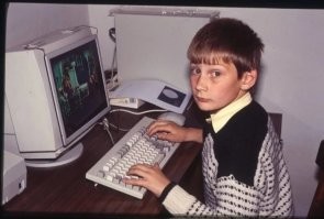 Разрешите докапаться! 
Во-первых, почему фото отзеркалили (фото 1 из поста, фото 2 - не зеркальное)
Во-вторых - пацан на сиськи смотрит.
Третье - это не фильм, это просто картинка. Компьютер у пацана точно на весь экран в таком качестве фильм не потянет. Почему? ПК у него слабоват для фильмов. Обратите внимание на подключение монитора - нет ускорителя 3dFX, если кто помнит, он ставился дополнительно к основной видеокарте, это говорит нам, о бюджетности его сборки. Так же на клавиатуре нет клавиш "Windows" они появились впервые в 1994 а массово в 98 и позднее. Обратите внимание на мышь, она без колесика-скрола, которое появилось в 1996 году. Посмотрите на монитор, на нем защитный экран, мода на них была в 80-е и первой половине 90-х. Так как ни клава ни мышь ни монитор не имеют желтого оттенка, значит ПК у парня относительно свеже купленый. А значит пк первой половины 90х, и фильм он тянуть не мог физически.