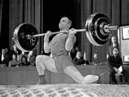 Добавлю... Так сказать, для полноты картины...

Алексей Вахонин в Стокгольме стал чемпионом мира, а ещё через год потряс всех на Играх в Токио. Тогда про его выступление писали все крупные газеты мира, прозвавшие советского атлета «чудо-штангистом». И писать было о чём. Борьба Вахонина с венгром Имре Фёльди была очень красивой и напряжённой. Перед толчком советский штангист проигрывал 2,5 кг и для победы должен был брать невероятный по тем временам вес в 142,5 кг. Причём в последней попытке.

Вахонин перед выходом на помост бросил уже праздновавшим победу венграм фразу «Х…во, вы шахтёров знаете», а затем легко толкнул штангу. Более того, когда судьи зафиксировали вес, он не бросил снаряд, а крикнул «Хо-па!» и поднял левую ногу. Фотография с этим трюком обошла весь мир. Его тренер Рудольф Плюкфельдер, кстати, там же в Токио победил в весовой категории до 82,5 кг.

Испытание медными трубами Вахонин не выдержал. Новая квартира в центре Шахт часто становилась местом пьяных гулянок. Причём устраивал их не только олимпийский чемпион, но гораздо чаще его жена. Супруга Алексея пропивала и заработки мужа, и вещи из квартиры. Штангист ещё держался на высоком уровне пару лет, даже выиграл чемпионат мира в Берлине, но дальше результаты резко пошли на спад, хотя он и оставался в тройке лучших в своей категории в СССР.

Переломным стал лично-командный чемпионат Европы 1968 года в Ленинграде. В случае победы Вахонину гарантировали поездку на Олимпиаду в Мехико. Но герой Токио не смог справиться с давлением и стал в итоге только третьим. Вечером после соревнований он напился и утром не явился на обязательную разминку.

Так трагически закончилась история олимпийского чемпиона Алексея Вахонина, который от безысходности искал спасения в бутылке, потому что стал никому не нужным.
После этого место в сборной СССР он потерял окончательно.

В 1970 году Алексей Вахонин завершил спортивную карьеру. Но так и не нашёл себя в обычной жизни. Сильно выпивавший олимпийский чемпион был не нужен ни Госкомитету по спорту, ни Ростовской области, ни даже Шахтам. Не мог он и тренером стать, так как не имел аттестата даже о восьмилетнем образовании. В итоге он вновь устроился на шахту, откуда был уволен за пьянку, стал подрабатывать разнорабочим и грузчиком. Жена вместе с сыновьями от него ушла, а Вахонин вконец опустился. Бывавшие в Шахтах его бывшие партнёры и друзья оставляли ему немного денег на жизнь и рассказывали, что в квартире нет ничего – даже обычного замка, кроме кровати с голыми пружинами и какого-то рванья.

Вахонин устроился могильщиком на местное кладбище, что позволяло ему регулярно иметь «живые» деньги. В последние годы вместе с ним в квартире жил один из сыновей, который вёл такой же образ жизни, как и отец. 1 сентября 1993 года после совместной пьянки сын ударил отца кухонным ножом в грудь. Соседи, испуганные внезапной тишиной, вызвали милицию и скорую, но сделать уже ничего было нельзя. Так закончилась история олимпийского чемпиона Алексея Вахонина, который от безысходности искал спасения в бутылке, потому что стал никому не нужным.