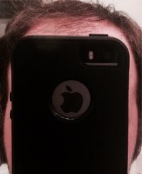 Это типичное селфи владельца айфона которые очень гордится своим тедлефоном - ему даже не сколько себя хочется снять, а именно телефон по тому это и закрыл им свое лицо

и вы вдумайтесь некоторые обладатели айфонов на столько преклоняются перед брендом эппл что специально для них делают чехлы с отверстием под логотип на задней крышке! 

(Может быть там в логотип сейчас встраивают сканер пальца я не следил, но на сколько я знаю скнер пальца у айфонов был на самом сенсоре... )