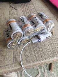 Что здесь так шокировало "подругу", что она "придумала" ? Я вижу 8 батареек по 1,5 вольта, соединены последовательно - это честные 12 вольт. Подключена автомобильная зарядка от прикуривателя (12 вольт). Поэтому да, телефон так вполне возможно подзарядить. У нас основы электротехники идут в школьном курсе физики, классе в шестом-седьмом вроде. Или в Америке такое только в специальных технических вузах преподают ?