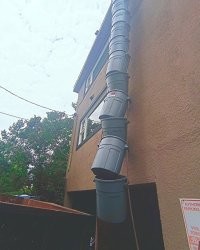 Это не водосточная труба, а штатное решение для сброса мусора в контейнер при ремонте зданий. Просто пока должным образом не настроенное или уже покореженное.
