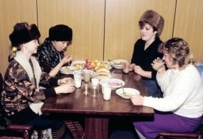 "Женщины обедают в ресторане не снимая шапок. Так было модно, ну, и чтобы не украли" 
В ресторанах снимали шапки, а на снимке какая-то из многочисленных тогда забегаловок скорее всего в обеденный перерыв