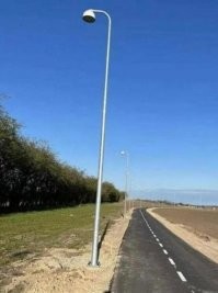Здесь все правильно, знаю это место. Здесь постоянно дуют очень сильные пассаты и сдувают свет от фонарей в сторону от дороги. Их специально повернули,  чтобы компенсировать влияние ветра. Теперь дорога освещена как надо.