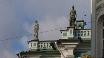 Всегда задавался вопросом, что это за статуя на правом углу зимнего дворца. Она резко контрастирует с остальным античным ансамблем.