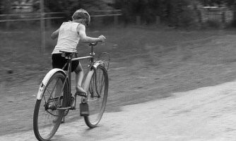 Это называлось "ездить в раму". С детскими и подросковыми велосипедами не все было хорошо, потому катались как могли. Но нелегко это было. Взрослый вел почти с тебя весом, без передач, сам изогнутый буквой С скачешь на педалях, попробуй подержи равновесие... а еще и рулить как-то надо...