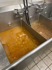 Мойщик прав. Это первые две мойки, с очень горячей водой. Для смыва большой грязи. А собственно чистовое мытьё происходит в третьей раковине, где как раз сейчас вода спущена. Должна быть ещё автомойка для ополаскивания (по типу автомобильной - посуда проходит на подносе через моечное отделение)