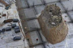 Тут вроде бы не дом, а могила. И судя по обстановке, её всё равно уберут, просто скорее всего время нужно на перезахоронение и бумажную волокиту.

В конце 90-х у двоюродного дяди жены (такая, седьмая вода на киселе родственники) пытались выкупить угловой дом, чтобы построить ТЦ, предлагали какие-то копейки реально, но там и дом халупа была конечно, но угол шоссейный, транспортная развязка, все дела. В общем сгорел вместе с этим дядей. А землю уже у родственников задарма купили потом.