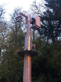 Это не видеонаблюдение, а метеостанция. Позволяет измерить температуру, влажность, наличие и уровни загрязнений воздуха.

А кольцо с шипами - чтобы никто (ни человек, ни животное) не могли попасть в зону измерения зонда: скорее всего он ИК или УФ (или сумма).
