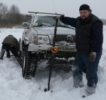 Странно они его вытаскивают. 

Там и надо-то, морду приподнять и пару досок толстых положить. 
Ну или ещё что, чтобы пандус образовался. 

Можно хайджеком за колесо. 
Ну или домкратом подлезть.