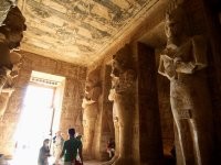 <<< солнечные лучи освещают камеру-обскуру >>>

Какая нахрен камера-обскура, даже в исходном понимании camera obscūra как "тёмная комната"? Там нет абсолютной темноты.



На входе в храм расположен зал с десятью колоннами, изображающих бога Осириса, но с чертами лица фараона Рамзеса II. 





За ним коридор длиной 65 метров и святилище со статуями богов.



Храм спроектирован таким образом, что дважды в год, в 6 часов утра 22 октября и 22 февраля, солнечные лучи проникают в коридор и освещают святилище с четырьмя сидящими статуями Амона, Ра-Хорахти, Птаха (все, как и статуи при входе, с лицами Рамзеса II) и Рамзеса II. 

По 6 минут солнцем освещены изображения Амона и Ра-Хорахти, 12 минут - фигура Рамзеса II (он в центре). На бога Птаха солнце не падает никогда, что символично, т.к. Птах - бог мёртвых. 

О подобной особенности храма узнали в 1874 году в ходе исследования процесса восхода и заката солнца. Для египтян этот день стал целым праздником. Они считают, что именно в этот день на свет появился фараон Рамзес II.