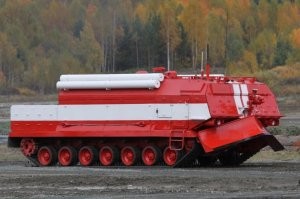Российская специальная пожарная машина   СПМ

Похожая на оба варианта, СПМ от предприятия Омсктрансмаш на самом деле является 60-тонной гусеничной машиной пожаротушения (Специальная пожарная машина СПМ). Она предназначена для случаев возгорания чего-то вроде полных взрывчатки складов, арсеналов, баз. Это основное назначение данной машины, которая прошла соответствующих комплекс испытаний, в том числе со стороны государственных органов.

Согласно данным с веб-сайта Омсктрансмаша, СПМ создана в 2012 году

ри её создании задействованы компоненты танков Т-72 и Т-80, бронированная, теплоизолированная и герметичная кабина убережёт экипаж от неблагоприятных условий внешний среды (именно к таким условиям относится огонь).

Экипаж специальной пожарной машины насчитывает три человека, её длина около 30 м, масса не более 60 тонн. Экипаж использует костюмы с теплоизоляцией и жаропрочностью, которые призваны защитить людей от влияния высоких температур. Также экипаж применяет индивидуальные средства очистки и фильтрации воздуха.

Если имеется угроза для жизни, экипаж может быстро покинуть кабину и операции выполняются дистанционно. Внутри СПМ находится примерно 25 кубических метров воды и прочих веществ для тушения огня, которые выбрасываются на расстояние до 100 м. В таком случае СПМ должна генерировать в своих резервуарах невероятное давление, так что под его струю попадать строго не рекомендуется. Через ствол за секунду проходит объём жидкости 100 литров. Подачей огнегасящего состава через лафетный ствол с наличием дистанционного управления занимается центробежный насос.

Обнаружить места возгорания помогают пять пуленепробиваемых стёкол, два тепловизора и система видеонаблюдения на основе четырёх камер. Защитить от высокой температуры призвана огнезащитная краска «Терма», огнестойкости которой хватает на 2 часа. Контакт с огнём в десятки раз повышает объём покрытия, в результате чего появляется негорючая пена с плохой теплопроводностью.

Имеются броневые противоосколочные экраны, совместно с бронированной кабиной они защищают людей и технику от осколков при подрыве осколочно-фугасного снаряда калибра 152 мм.

Чтобы добраться к местам возгорания и дать дорогу другой технике, СПМ использует бульдозерное оборудование   клиновидный отвал.

Скорость движения СПМ по шоссе при полной массе достигает 40 км/ч, запас хода достигает 250 км.