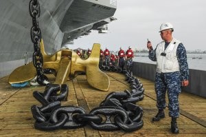 Вбить по всему острову штырей штук сто на равном удалении, соединить тросами, а уже получившуюся формацию прикрепить к корабельному якорю, исходя из массы плавающего острова.  Может там от эсминца нужен якорь, а может от линкора.  Купить списанный якорь у тамошнего ВМФ и не устраивать онанизм каждый год.  
Вместо якоря можно просто со свалки школьный автобус выкупить, затопить его и силами двух-трёх водолазов забить его списанными же радиаторами отопления, после чего уже прикрепить остров в нужной точке. Вместо цепи можно синтетический канат какой использовать, один фиг там течения особого нет, глубина скорее всего небольшая,  так что на пару сотен лет хватит,  потом можно канат заменить. И то не факт, сейчас химическая промышленность такие синтетические канаты изготавливает, что прям на века, если он ни обо что не трётся, а тупо фиксирует два объекта.
Я не специалист, но это первая идея которая пришла ко мне в голову. Хотя возможно, для тамошних жителей, эта движуха что-то вроде старой доброй традиции, как знак единения и общественно полезного труда рядом с товарищами.  Либо я чего-то не учёл, что помешает заякорится, ибо я  - диванный эксперт, и вообще пойду учебники в портфель соберу, а то мамка наругает.