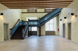 В Нарве есть старинная ратуша(фото тех времён ниже). Про нее ходит много легенд, говорят, там есть привидения, в чем я однажды лично убедился.
В то время она пустовала, а мой друг работал там сторожем. Поэтому мы иногда собирались там пропустить ромашку.
Вот однажды сидели втроём, мне захотелось в туалет. А туалет находится в другом крыле здания, надо пройти по коридору, через зал(на фото) и в другой коридор. Была ночь, но в зале и туалете есть окна, так что свет включать не требовалось, сумрак, но дойти можно.
С нами был ротвейлер, Джесси. Он с детства меня знал, и обычно слушался. Я пошел, позвал Джесси с собой, выхожу из туалета, Джесси стоит, ждёт меня. Погладил ее мимоходом и пошел обратно. Захожу в комнату, а Джесси там сидит.  Говорю, не понял, а как ты меня обогнала, ты ж сзади шла? Мужики на меня смотрят ошалело и говорят - так она и не выходила. Тут и я ошалел -  говорю, а кого ж я тогда только что погладил? Разгадки мы так и не нашли. Того собакена я толком не рассмотрел, черный пёс в темноте, что там рассмотришь, да я и не приглядывался, ведь был уверен, что это Джесси. И выпито-то было всего полтора на троих, для трёх мужиков это ни о чем.

Так же там ночами творились странности с дверью в каморку. Я обычно спал на диване у двери, в двери есть замок, который открывается только нажатием на ручку. Так вот, дверь частенько открывалась ночью сама. Сначала было страшновато, выбегал в коридор смотреть, а потом привык и забил на это, тупо вставал и закрывал опять. Иногда были слышны шаги в коридоре или на верхнем этаже, но никого там не было, проверяли не раз.

Кстати, сейчас ратушу отреставрировали(фото), там теперь горуправа. Надеюсь, привидения теперь досаждают нашим чиновникам.