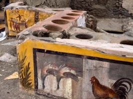 Помпеи, как историческая "консерва" - это вообще уникальное явление.

Вот, к примеру, термополии (фудкорт). В выемках стояли кувшины с горячей едой (типа современных мармитов), которые подогревались снизу изнутри. Еще видны фрески с "меню". 
Подошел "мне курицу в лаваше и овощей побольше", заплатил и пошел искать лупанарий. (Кстати, в Помпеях и это нашли. С ценником, рекламой и афишами).