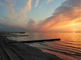 Не исключаю что на фото присутствуют фильтры. Однако ваш вопрос странный. ГДЕ розовый цвет должен быть на домах и деревьях, если рассветное фото показывает только небо, тучи, море, песок и волнорезы? Домов и деревьев там нет. А фото с закатом розового не имеет. И на деревьях нет никакого оттенка, потому что они освещены сзади и могут быть лишь тёмные, почти черные. На здании нет отблеска, поскольку уже включена подсветка и она очень сильно меняет цветность стен. Тут я уверена что фото вполне натуральное. Ну может лишь чуть усилено небо по цвету, хотя видела вживую такую интенсивность. Наши закаты реально невероятные по сочности красок.  Не зря называют их янтарными. Вот ещё примеры. В принципе тут и фильтры не особо нужны. Своими глазами все такое можно увидеть каждый день.