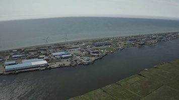 Это пос. Октябрьский. Вполне себе существующий, он просто прям на косе, так что старые общаги подмыло.