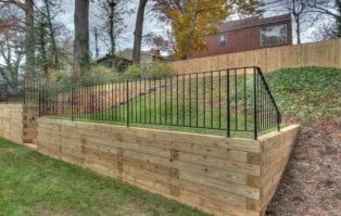 Забор просто выше. В смысле, низ забора. Ракурс съёмки такой. 

Примерно так.