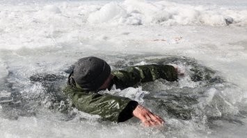 Со страховкой - не считается.  Пускай без троса повторит. Это будет пипец как смело, глупо и опасно.  А так, по сути она просто не выныривая в  холодной воде 122 метра проплыла.  Чуть - что, с курсу не собьётся, вокруг под водой, несколько страхующих водолазов.. на точках входа и выхода к тросу шарик приделан, и даже если она - сознание потеряет, с  любой стороны можно потянувши за трос - её вытащить. 
Ну такое себе.
Я конечно с дивана рассуждаю, но и какого-то супер прям подвига в  этом не вижу.  На мой взгляд, в целом - тупо, плавать подо льдом, если ты не какой-нить мега морской котик или спасатель,  в чьих должностных обязанностях, значится наличие такого умения.
Я вот, малой,  в деревне Шамордино (Брянская область) зимой в  90-х, под лёд провалился, в шубе.  Там кто-то полынью во люду сделал ради рыбной ловли,  она корочкой за ночь, ледяной покрылась и снегом её присыпало.. а я в нарушение запретов родителей, бегал на лёд играть, наступил и провалился.. меня течением под лёд занесло. Благо речка неглубокая (максимум 1.5 метра.. хотя и я тогда был метр с кепкой), я на морально волевых, под водой, против течения реки смог отталкиваясь от дна, обратно к полынье вернуться и в пропитанной водой шубе (она тяжеленная была) за кромку льда схватиться и выползти на поверхность,  дойти до дома, получить ремня и обсохнуть.  Это довольно страшно: внезапно, в зимней одежде, уйти под лёд, не иметь возможность всплыть и вдохнуть воздуха, сориентироваться, найти нужное направление и выкарабкаться, потому что вокруг никого нет, кто бы мог прийти на помощь, а ты даже из воды руку показать не можешь или оттолкнувшись от дна, всплыть и позвать на помощь.. пока не найдёшь место, где льда нету.
С тех пор, я на эти "смелые" заплывы подо льдом, считаю какой-то глупостью,  а заплывы со страховкой и поддержкой , так вообще как на детский сад... нет угрозы смерти, нет адреналина, нет геройства..  ты просто подготовленный в минимальной одежде и при ластах, проплываешь какой-то отрезок, на запасе воздуха в лёгких.. Ребячество. Повтори  это одна, против течения, без страховки и без людей вокруг, не зная где точно точка всплытия на поверхность,  записав свой рекорд чисто на камеру со штатива.  Даже если ты  это сделаешь без шубы и валенок,  я скажут -  что это круто. Это сила духа, и презрение к опасности смерти. Это по настоящему, ибо тут ты в противовес рекорду, ставишь собственную жизнь..  А так.. можно сказать что у меня "проф. деформация", и я не вижу в этом ничего кроме глупости и "рекорда" там, где другие просто не собираются таким заниматься, а не не могут сделать тоже самое.
Так что, сугубо моё личное субъективное мнение - дурость это и ничего такого уж особенного, учитывая заранее предпринятые меры безопасности, вкупе с подготовкой пловца.