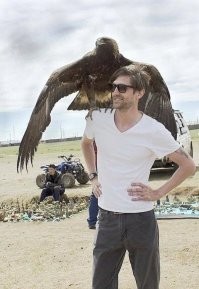 это фотошоп - если бы орёл реально сел ему на плечо, то он бы не улыбался, а скорчился от боли