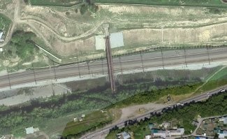 это не мост, а две трубы большого диаметра над ж/д полотном (по этому и такой контраст в качестве картинки с соседней территорией), проходящих над этим полотном на высоте пятиэтажного дома.

люди ходили (двадцать минут экономии!), падали, убивались, но другие продолжали ходить. противостояние длилось долго, не одно десятилетие, но власти победили. вроде. это не точно.