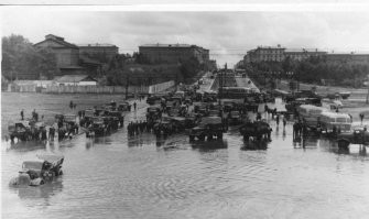 Снимок №5 "Потоп на пл.Труда" из серии снимков 1959 года сделаных жителем Восточного посёлка (это адрес такой) Георгием Викторовичем Жаннин-Перро. Он вообще много снимал Новосибирск и вот часть этой серии. В тот летний день с юго-востока пришла чёрная, налившаяся над Обью, избытком воды, она сначала обрушила водяной шквал на строящийся район "Башня", а потом накрыла Первый соцгород, где все переулки и улицы были мощёны булыжником, а центральную улицу Станиславского упиравшуюся в только, что построенный и открытый новый путепровод под Транссибом, свеже заасфальтированную для пуска троллейбусного движения к заводам.  Ливнёвка на площади Труда в мгновение ока была забита обломками смытого асфальта и площадь превратилась в озеро. Но кому проблемы, а детям и тут игра - вода-то пришла тёплая, нагретая взломанным дорожным покрытием. И вот благодаря Георгию Викторовичу, мы можем увидеть результат работы того ливня.