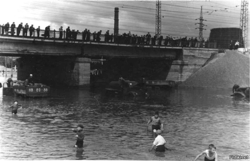 Снимок №5 "Потоп на пл.Труда" из серии снимков 1959 года сделаных жителем Восточного посёлка (это адрес такой) Георгием Викторовичем Жаннин-Перро. Он вообще много снимал Новосибирск и вот часть этой серии. В тот летний день с юго-востока пришла чёрная, налившаяся над Обью, избытком воды, она сначала обрушила водяной шквал на строящийся район "Башня", а потом накрыла Первый соцгород, где все переулки и улицы были мощёны булыжником, а центральную улицу Станиславского упиравшуюся в только, что построенный и открытый новый путепровод под Транссибом, свеже заасфальтированную для пуска троллейбусного движения к заводам.  Ливнёвка на площади Труда в мгновение ока была забита обломками смытого асфальта и площадь превратилась в озеро. Но кому проблемы, а детям и тут игра - вода-то пришла тёплая, нагретая взломанным дорожным покрытием. И вот благодаря Георгию Викторовичу, мы можем увидеть результат работы того ливня.