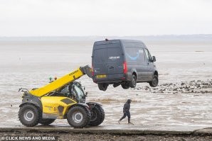 текст не выдуман.
это гугль переводчик с британского оригинала daily mail.  в оригинале так и стоит, что он хотел проехать во время отлива, но соскочил с тропы и увяз.
водитель сам позвонил в амазон своему начальнику и доложил о прошествии, амазон нанял местного фермера с телескоп-погрузчиком.