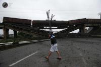 A man walks past a destroyed railroad bridge which fell over a main road leading to the eastern Ukrainian city of Donetsk, near the village of Novobakhmutivka. MAXIM ZMEYEV/REUTERS
