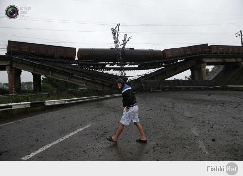 A man walks past a destroyed railroad bridge which fell over a main road leading to the eastern Ukrainian city of Donetsk, near the village of Novobakhmutivka. MAXIM ZMEYEV/REUTERS