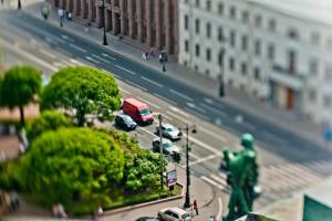 Спешу тебя огорчить, это не фотошоп. Это, скорее всего, Гелиос 44-2(3,4...n) и некий эластичный удлинняющий предмет, например пыльник рулевой рейки как у меня. Пыльник режется определённой длинны, с одной стороны ставится байонетное соединение с фотосистемой (никон, кэнон, сони, пентакс и т.д.) с другой как раз объектив. Далее, объектив прижимается к тушке и смещается немного вниз-вверх-влево-вправо в любой плоскости, иногда сразу в двух, в результате чего происходит смещение резкости (ГРИП). В результате чего появляется ощущение, что всё на фотографии игрушечно. Это называется, если я не ошибаюсь, шифт-объектив. Вот что в своё время получилось у меня: