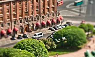 Спешу тебя огорчить, это не фотошоп. Это, скорее всего, Гелиос 44-2(3,4...n) и некий эластичный удлинняющий предмет, например пыльник рулевой рейки как у меня. Пыльник режется определённой длинны, с одной стороны ставится байонетное соединение с фотосистемой (никон, кэнон, сони, пентакс и т.д.) с другой как раз объектив. Далее, объектив прижимается к тушке и смещается немного вниз-вверх-влево-вправо в любой плоскости, иногда сразу в двух, в результате чего происходит смещение резкости (ГРИП). В результате чего появляется ощущение, что всё на фотографии игрушечно. Это называется, если я не ошибаюсь, шифт-объектив. Вот что в своё время получилось у меня: