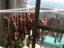 Не фотошоп, но и не бекон. Большинство китайских семей с наступлением зимы делают домашние колбаски "Сян чан". Хорошо очищенные свиные кишки забивают фаршем и на всю зиму вывешивают на балкон или просто на улицу для "созревания". В сыром виде не употребляется - перед употреблением колбаски приготавливаются в пароварке.