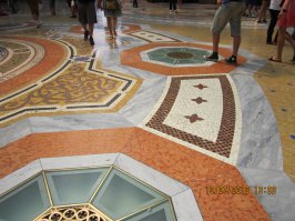 Мозаичный, мраморный пол миланского Пассажа. На одном из медальонов мозаики изображен бык. его гениталий уже не видно...на них на пятке левой ноги, против часовой стрелки  туристы делают три оборота.  в этом месте уже ямка...Снять не удалось- всегда занято.