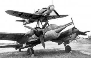 Ju 88 "Mistel"
Германия - 1943
В июле 1943 года фирма Junkers получила задание переоборудовать Ju 88-А в беспилотный самолет-снаряд (в Luftwaffe они имели обозначение "Mistel"), управляемый из одноместного истребителя, укрепленного над фюзеляжем снаряда-носителя. Пилот истребителя вел спарку до точки расцепления, в которой он направлял Ju 88 на цель и отстыковывался.
Истребитель крепился к самолету-снаряду на стальных стойках, укрепленные над центропланом Ju 88 по обе стороны фюзеляжа и сходившиеся под фюзеляжем управляемого самолета вместе с V-образной стойкой от фюзеляжа носителя, образуя два треножника. Верхние точки треножников крепились к главному лонжерону истребителя. Еще одна подпружиненная стойка шла к хвостовой части истребителя. Когда пилот освобождал истребитель, задняя стойка откидывалась назад вдоль фюзеляжа. При касании последнего срабатывал замыкатель, который приводил в действие систему отцепки основных креплений на треножниках. Таким образом предотвращался возможный удар хвостовой части истребителя о заднюю стойку.
Первые 15 Ju 88-А4 были переоборудованы в июле 1943 года. Mistel из Ju 88-А4 с Messerschmitt Bf 109-F, получил обозначение "Beethoven".
Прототип Mistel: Ju 88-А4/Bf 109-F Вначале в Mistel переоборудовали отслужившие свой срок конструкции Ju 88. Из кабины убрали лишнее оборудование, оставив лишь два места экипажа для обучения. Такие машины, получившие обозначение 1, использовали для обучения. Носовой отсек мог быть заменен 3800-кг боеголовкой при помощи быстроразъемных болтов.
Эта боеголовка была успешно испытана на старом французском линкоре-цели "Ошен" во второй половине 1943 г. Проводились опыты и по поражению фортификационных сооружений. При этом тонный стальной стержень кумулятивного ядра пробивал 20 м бетон. Окончательные испытания боеголовки проводились в Peenemünde с апреля по май 1944 г.

Mistel: Ju 88-А4/Bf 109-F Предусматривались два основных приема боевого использования. При первом взлет и полет к цели осуществлялся только при работе двигателей нижнего самолета, а двигатель верхнего самолета запускался только вблизи цели. Второй способ предусматривал использование совместной работы моторов двух машин, а питание бензином верхнего самолета шло из баков нижнего. Когда связка достигала цели, пилот переводил ее в пологое пикирование. На безопасной дистанции истребитель отцеплялся, а беспилотный самолет пикировал на цель.

Первые пять Mistel 1 поступили на вооружение IV/КG 101. Первый боевой вылет был совершен 24 июня 1944 г. Вылет не удался, так как истребителю пришлось отцепиться еще до цели из-за появления ночного истребителя Mosquito.
Вскоре после этого четыре Mistel под прикрытием истребителей Вf 109-G атаковали суда союзников в заливе Сены. Атака была осуществлена при свете осветительных ракет, но результаты не удалось пронаблюдать из-за дыма горящих судов. Разведка на следующий день показала, что все цели были поражены, но ни одно судно не затонуло.
Воодушевленные этим успехом, Luftwaffe заказали заводу в Mockau (Leipzig) еще переоборудовать в Mistel еще 75 ремонтировавшихся там Ju 88-G1. На этот раз это была связка Ju 88-G1 и Fw 190-A6 или Fw 190-F8, так как их моторы также работали на 95-октановом бензине (Mistel 2; учебный вариант S2). К сожалению, комбинация Ju 88-G с полными топливными баками и боеголовкой с Fw 190 была значительно перезагружена, и при взлете случались аварии из-за разрыва пневматиков. После потери нескольких Mistel при взлете, под фюзеляжем была установлена третья сбрасываемая стойка. Этот вариант получил обозначение Mistel 3.

10.10.1944 на базе IV/КG 101 была образована III/КG 66, предназначенная исключительно для использования Mistel, но уже через 10 дней ее переименовали в II/КG 200. К этому времени было решено использовать все имеющиеся Mistel для атаки британского флота в Scapa Flow. Операция была намечена на декабрь 1944 г. Для этой операции на аэродромах в Дании было собрано 60 Mistel вместе с 5./КG 200, самолеты которой должны были освещать цели. Постоянно стоявшая плохая погода задерживала начало операции, а когда она окончательно прояснилась, установилась полная луна. Неповоротливые Mistel 2, развивавшие не более 380 км/ч могли стать легкой добычей британских ночных истребителей.
Следующее нападение планировалось на март 1945 против советских военных заводов. Было заказано 125 Mistel, 100 из которых требовались для этой операции. В марте аэродромы в Восточной Пруссии, которые планировалось использовать для операции "Eisenhammel", были заняты советскими войсками. Позже II/КG 200 предприняла отдельные атаки мостов на восточном и западном фронтах.
Первой их атакой стал налет 9 марта четырех Mistel из состава II/КG 200 на мосты у Görlitz на Neiße. Оба моста были поражены. Mistel из II/КG 200 использовались для налетов на мосты через Рейн. С апреля для этих же целей привлекались подразделения КG 30, также перевооруженные на Mistel. Почти все Mistel были использованы в этих атаках, а их пилотов вскоре перевели в истребительные части.
Темпы переоборудования возросли и теперь в самолеты-снаряды переделывали строящиеся на заводе Junkers в Bernburg Ju 88-G10 и Ju 88-H4 прямо на сборочной линии. Связка Ju 88-G10/Fw 190-A8 обозначили как "Mistel 3C". Самолет отличался вставкой перед крылом 2.75 м фюзеляжной секции. Fw 190, оснащался парой 270 л накрыльевых баков и подфюзеляжным 300 л баком. Второй и третий фюзеляжные баки Mistel предназначались под 95-октановый бензин, который Fw 190-A8 использовал во время полета в связке. Остальные баки заливались 87-октановым бензином. Аналогичный вариант из связки Ju 88-H4/Fw 190-A8 получил обозначение "Mistel 3B".
Одна из модификаций Mistel 3B с экипажем в три человека служила сверхдальним самолетом наведения "Fuehrungmaschine", неся на себе Fw 190-A8 в качестве собственного эскорта. Mistel оснащался локатором сантиметрового диапазона и имел оборонительное вооружение из пулемета МG 131 в задней части кабины. Под центропланом можно было подвесить два 900 л сбрасываемых бака. Один из последних Mistel состоял из Ta 152-H и Ju 88-G7.
Всего было построено около 250 Mistel различных модификаций.