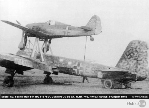 Ju 88 "Mistel"
Германия - 1943
В июле 1943 года фирма Junkers получила задание переоборудовать Ju 88-А в беспилотный самолет-снаряд (в Luftwaffe они имели обозначение "Mistel"), управляемый из одноместного истребителя, укрепленного над фюзеляжем снаряда-носителя. Пилот истребителя вел спарку до точки расцепления, в которой он направлял Ju 88 на цель и отстыковывался.
Истребитель крепился к самолету-снаряду на стальных стойках, укрепленные над центропланом Ju 88 по обе стороны фюзеляжа и сходившиеся под фюзеляжем управляемого самолета вместе с V-образной стойкой от фюзеляжа носителя, образуя два треножника. Верхние точки треножников крепились к главному лонжерону истребителя. Еще одна подпружиненная стойка шла к хвостовой части истребителя. Когда пилот освобождал истребитель, задняя стойка откидывалась назад вдоль фюзеляжа. При касании последнего срабатывал замыкатель, который приводил в действие систему отцепки основных креплений на треножниках. Таким образом предотвращался возможный удар хвостовой части истребителя о заднюю стойку.
Первые 15 Ju 88-А4 были переоборудованы в июле 1943 года. Mistel из Ju 88-А4 с Messerschmitt Bf 109-F, получил обозначение "Beethoven".
Прототип Mistel: Ju 88-А4/Bf 109-F Вначале в Mistel переоборудовали отслужившие свой срок конструкции Ju 88. Из кабины убрали лишнее оборудование, оставив лишь два места экипажа для обучения. Такие машины, получившие обозначение 1, использовали для обучения. Носовой отсек мог быть заменен 3800-кг боеголовкой при помощи быстроразъемных болтов.
Эта боеголовка была успешно испытана на старом французском линкоре-цели "Ошен" во второй половине 1943 г. Проводились опыты и по поражению фортификационных сооружений. При этом тонный стальной стержень кумулятивного ядра пробивал 20 м бетон. Окончательные испытания боеголовки проводились в Peenemünde с апреля по май 1944 г.

Mistel: Ju 88-А4/Bf 109-F Предусматривались два основных приема боевого использования. При первом взлет и полет к цели осуществлялся только при работе двигателей нижнего самолета, а двигатель верхнего самолета запускался только вблизи цели. Второй способ предусматривал использование совместной работы моторов двух машин, а питание бензином верхнего самолета шло из баков нижнего. Когда связка достигала цели, пилот переводил ее в пологое пикирование. На безопасной дистанции истребитель отцеплялся, а беспилотный самолет пикировал на цель.

Первые пять Mistel 1 поступили на вооружение IV/КG 101. Первый боевой вылет был совершен 24 июня 1944 г. Вылет не удался, так как истребителю пришлось отцепиться еще до цели из-за появления ночного истребителя Mosquito.
Вскоре после этого четыре Mistel под прикрытием истребителей Вf 109-G атаковали суда союзников в заливе Сены. Атака была осуществлена при свете осветительных ракет, но результаты не удалось пронаблюдать из-за дыма горящих судов. Разведка на следующий день показала, что все цели были поражены, но ни одно судно не затонуло.
Воодушевленные этим успехом, Luftwaffe заказали заводу в Mockau (Leipzig) еще переоборудовать в Mistel еще 75 ремонтировавшихся там Ju 88-G1. На этот раз это была связка Ju 88-G1 и Fw 190-A6 или Fw 190-F8, так как их моторы также работали на 95-октановом бензине (Mistel 2; учебный вариант S2). К сожалению, комбинация Ju 88-G с полными топливными баками и боеголовкой с Fw 190 была значительно перезагружена, и при взлете случались аварии из-за разрыва пневматиков. После потери нескольких Mistel при взлете, под фюзеляжем была установлена третья сбрасываемая стойка. Этот вариант получил обозначение Mistel 3.

10.10.1944 на базе IV/КG 101 была образована III/КG 66, предназначенная исключительно для использования Mistel, но уже через 10 дней ее переименовали в II/КG 200. К этому времени было решено использовать все имеющиеся Mistel для атаки британского флота в Scapa Flow. Операция была намечена на декабрь 1944 г. Для этой операции на аэродромах в Дании было собрано 60 Mistel вместе с 5./КG 200, самолеты которой должны были освещать цели. Постоянно стоявшая плохая погода задерживала начало операции, а когда она окончательно прояснилась, установилась полная луна. Неповоротливые Mistel 2, развивавшие не более 380 км/ч могли стать легкой добычей британских ночных истребителей.
Следующее нападение планировалось на март 1945 против советских военных заводов. Было заказано 125 Mistel, 100 из которых требовались для этой операции. В марте аэродромы в Восточной Пруссии, которые планировалось использовать для операции "Eisenhammel", были заняты советскими войсками. Позже II/КG 200 предприняла отдельные атаки мостов на восточном и западном фронтах.
Первой их атакой стал налет 9 марта четырех Mistel из состава II/КG 200 на мосты у Görlitz на Neiße. Оба моста были поражены. Mistel из II/КG 200 использовались для налетов на мосты через Рейн. С апреля для этих же целей привлекались подразделения КG 30, также перевооруженные на Mistel. Почти все Mistel были использованы в этих атаках, а их пилотов вскоре перевели в истребительные части.
Темпы переоборудования возросли и теперь в самолеты-снаряды переделывали строящиеся на заводе Junkers в Bernburg Ju 88-G10 и Ju 88-H4 прямо на сборочной линии. Связка Ju 88-G10/Fw 190-A8 обозначили как "Mistel 3C". Самолет отличался вставкой перед крылом 2.75 м фюзеляжной секции. Fw 190, оснащался парой 270 л накрыльевых баков и подфюзеляжным 300 л баком. Второй и третий фюзеляжные баки Mistel предназначались под 95-октановый бензин, который Fw 190-A8 использовал во время полета в связке. Остальные баки заливались 87-октановым бензином. Аналогичный вариант из связки Ju 88-H4/Fw 190-A8 получил обозначение "Mistel 3B".
Одна из модификаций Mistel 3B с экипажем в три человека служила сверхдальним самолетом наведения "Fuehrungmaschine", неся на себе Fw 190-A8 в качестве собственного эскорта. Mistel оснащался локатором сантиметрового диапазона и имел оборонительное вооружение из пулемета МG 131 в задней части кабины. Под центропланом можно было подвесить два 900 л сбрасываемых бака. Один из последних Mistel состоял из Ta 152-H и Ju 88-G7.
Всего было построено около 250 Mistel различных модификаций.
