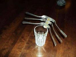 Вот тут сомневаюсь что без фотошопа дело обошлось.
Центр тяжести вилок с монетами приходится на монету в центре, а место баланса на первой монете. Упадет сто процентов.
Если бы вилки были разными, например первый две имели ручки подлиннее, то это компенсировало бы силу притяжения. Хорошо бы видео на этот момент.
Хотя кому это интересно ))