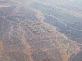 Небоскребы Дубая,облака,поля орошения и заснеженные горы.