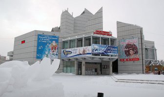 «Бастилия» — культовое здание Благовещенска, здание-монстр. Одной из последних ее жертв был маленький кирпичный домик. Вспоминая о его злосчастной судьбе, трудно поверить в то, что «Бастилия» закрыла этот свой черный список.

Последняя жертва «Бастилии»

Общественно-культурный центр не имеет официального названия даже спустя два года после открытия. Назвать его «Бастилией» власти не могли, а другого названия сама «Бастилия» не принимает, это имя она выбрала себе сама и так ее зовет народ. А ведь сколько конкурсов проводилось по этому поводу, сколько комиссий совещалось…

Для тех кто не в теме кратко скажем, что это здание некогда было самым известным долгостроем Благовещенска. Его железобетонные конструкции десятилетиями возвышались в центре города. В лунную ночь «Бастилия» выглядела не просто зловеще, она внушала ужас.

Её начали строить глубоко в СССР, еще до перестроек. Тогда она была «драматическим театром». Ее строили так медленно, с такими проволочками, что даже проплывавший на пароходе по Амуру какой-то советский писатель, живописуя рассвет социализма, написал, как огнями ослепило его здание драмтеатра на берегу реки. И хотя он видел лишь остов здания, его книга была издана много позже путешествия, и автор не мог представить себе, что здание до сих пор не достроено. Вышел конфуз.

Заброшенная стройка стала местом прибежища бомжей, местом тусовки неформальной молодежи, притоном наркоманов. Там то и дело находили трупы, упавших с конструкций, убитых кем-то или просто умерших. Периодические трагедии в «Бастилии» поднимали мелкие волны общественного негодования, но ничего не менялось, строительная площадка зарастала не просто бурьяном, а диким лесом уже.

Иногда возникали проекты то по ее достройке, то по сносу. Но все было впустую, менялись времена, люди, нравы, а «Бастилия» оставалась сама собой. Сколько уж там разных жертв на ее счету, поломанных судеб, то уж неизвестно и не сосчитать. Бывший губернатор Коротков рискнул ее достроить, и с перерывами стройка велась, но и ему не суждено было изменить ее суть. Скорее наоборот: перед самым открытием Короткова сняли, а утвержденное им название ОКЦ — «Албазин» следующий губернатор отменил и другого уже не давали.

Похоже, попытка обозвать «Бастилию» сыграла мистическую роковую роль в судьбе самого Короткова: утвердил название и через три дня получил указ Президента об отстранении. Не любит «Бастилия» такого вот панибратства. Может на ее месте было какое-нибудь священное место древних джурдженей? Очень на то похоже.

Конечно, она давно расчистила пространство вокруг себя, целый городской квартал снесли в свое время ради нее, но каким-то чудом совсем рядом сохранился маленький, еще дореволюционный домик. Почему его не снесли в советские времена, как он остался стоять рядом с монстром все эти десятилетия – известно теперь только самой «Бастилии». И уже одевшись в белый мраморный саван, она словно оглядевшись и увидев у себя под ногами это несчастный домик – как всегда жестко и безжалостно, одним ударом прикончила и его.

Формально дело было так.

Власть в области сменилась, на место Короткова, был назначен Колесов, а тут как раз и подоспело официальное открытие ОКЦ. Новый губернатор поехал посмотреть «объект» и увидел красный домик, явно мешавшийся под ногами у «Бастилии» и портивший вид. Приказал немедленно снести.

Дело в том, что избавиться от домика пытались и до Колесова, но он находился в частной собственности, им владела некая гражданка по фамилии Левцкая, которая толи хотела открыть там кафе, толи просто пыталась получить побольше денег с города, раз уж такая сложилась ситуация. В общем, шли затяжные переговоры с собственником домика о цене.

Возможно, они бы шли и до сих пор, если бы не назначение Колесова, который отличался своеобразным взглядом на мир. В общем, он дал мэру Мигуле неделю на решение вопроса и уехал. А Колесова тогда все сильно испугались, противоречить ему не смели, он был страшнее любого закона для посткоротковской чиновной братии.

Сына той самой гражданки Левицкой вызвали к вице-мэру, который предложил ей домик этот быстро подарить городу, мол, а то хуже будет. Гражданка отказалась. Ночью к домику с милицейским сопровождением подъехал «Камацу», собственница с родственниками собирались держать оборону, но их быстро под белые рученьки спровадили и экскаватор раскрошил домик вместе со всем содержимым. К утру все было кончено.

Теперь лишь фотографии снятые в свое время со стороны Амура напоминают об этом злосчастном доме, а «Бастилия» стоит на берегу Амура в гордом одиночестве.

Мы не будем судить о соблюдении в нашем городе законности, о правомерности и адекватности действий различных людей. В этой рубрике мы рассказываем о Благовещенске и его городских легендах. «Бастилия» — одна из них. Не по своим масштабам, ни по архитектуре она никогда не соответствовала тихой провинциальной столице Приамурья. История ее появления загадочна, а ее судьба по-своему уникальна.

Находись такое здание в каком-нибудь туристическом центре, оно бы стало местом паломничества любопытных. «Бастилию» недаром так назвал народ, она коверкает судьбы связавшихся с ней людей не хуже своей французской тезки. Только ту разрушали, но в своей новой реинкарнации на берегу Амура символ зла продолжает жить.

Маленький красный домик, стал очередной жертвой «Бастилии», но никто не поверит, что последней. Сейчас там выступают заезжие «биланы» и все кажется вполне благополучным. Но если завтра рухнут, признанные абсолютно надежными после двадцати лет стояния под снегом и дождем, ее перекрытия, или вспыхнет пожар, или случится что-нибудь не менее ужасное, то разве кто-нибудь в Благовещенске этому удивится?