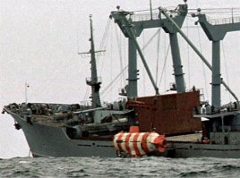 A C-5 Galaxy is loaded with people and equipment from the Deep Submergence Unit, Naval Base Coronado. The C-5 is bringing two Super Scorpio robotic rescue vehicles to Russia to assist in the rescue.В пятницу же ВМФ России обращается за помощью к командованию тихоокеанского флота США. Американцы решают послать на Камчатку глубоководный аппарат "Скорпион" со своей базы в Калифорнии: с его помощью можно перекусить тросы, в которых запутался батискаф.

Почему ВМФ не мог справиться сам

Действительно, смог бы? Если попытаться ответить на этот "гипотетический вопрос", то картина вырисовывается весьма плачевная. Согласно инструкции на борту судна, с которого производилось погружение АС-28, должен был быть второй аналогичный аппарат, который теоретически мог бы спасти первый, попавший в аварийную ситуацию. Однако второй батискаф с "Георгия Козьмина" списали из-за его аварийного состояния. В итоге единственное, что мог сделать базовый корабль для спасения терпящей бедствие мини-субмарины, это послать сигнал о помощи в штаб. Кстати, как раз в этот момент главком ВМФ Владимир Куроедов находился в госпитале, поэтому руководство спасательной операцией принял на себя его заместитель, адмирал Владимир Масорин.

На следующий день в район аварийных работ было направлено сразу 10 судов ВМФ, в числе которых находилось судно-спасатель "Алагез", также согласно инструкции укомплектованное двумя глубоководными батискафами… Но на самом деле оно не имело на своем борту ни одного - оба аппарата задолго до 4 августа также были сданы в ремонт. А главный специалист по глубоководным погружениям "Алагеза", под началом которого находилась такелажная служба и водолазы, способные работать на глубине свыше 100 метров, в этот день находился в отпуске… Таким образом, даже оборудованный для глубоководной работы корабль ничем не мог помочь затонувшему батискафу, кроме траления вместе с остальными 9-ю судами (кстати, "Алагез" еще 5 лет назад хотели продать на металлолом в Южную Корею, однако после гибели АПЛ "Курск" решено было оставить судно на балансе ВМФ на случай экстренных спасательных подводных работ).

В пятницу же из Владивостока было вызвано судно-спасатель "Саяны", батискафы которого находятся в исправном состоянии. Однако придти на место работ этот корабль мог только через три дня…

Вот и получилось, что ближайшим к бухте Березовая исправным глубоководным спасательным аппаратом оказался британский "Скорпион-45", который и осуществил большую часть работ. Российскому министру обороны оставалось только превозносить "морское братство", а МИДу РФ - выражать глубокую признательность Великобритании, США и Японии за их готовность оказать помощь в спасении моряков батискафа АС-28.